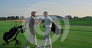 Golf players shaking hands on grass field. Two friends meeting play on weekend.