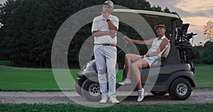 Golf players sit cart on course. Sport couple enjoy activity in driving golf car