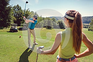 Golf playing woman and man at the tee