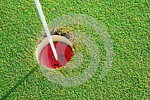 Golf practice putting green hole and marked with a red sign