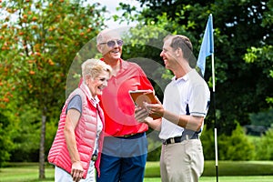 Golf pro with senior woman and man analyzing results