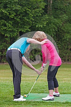 Golf pro teaching a lady golfer