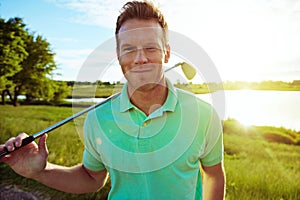Golf putts me in a good mood. Portrait of a young man spending the day on a golf course. photo