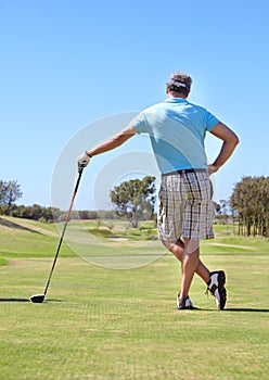 Golf, rear view and old man with driver outdoor for training, hobby and sports on blue sky background. Club, behind and
