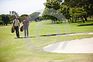 Golf, sports and men walking with bag after practice or training on green lawn for partnership or collaboration. Friends