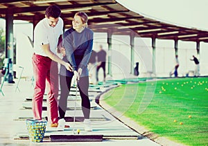 Golf trainer teaches a woman game