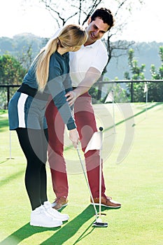 Golf trainer teaches a woman game