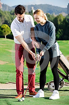 Golf trainer teaches a woman game