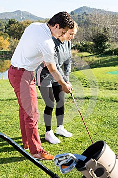 Golf trainer teaches a woman game