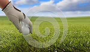 Golfball on green grass golf course, blue cloudy sky background