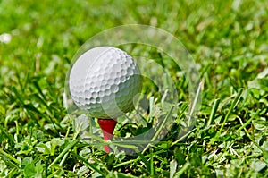 Golfball on red tee on the grass