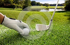 Golfball and stick on green grass golf course, blue cloudy sky background