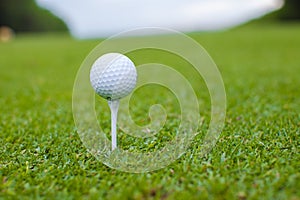 Golfball on a tee against the golf course