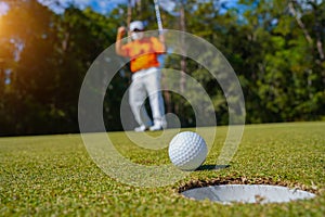 Golfer action to win after long putting golf ball on the green golf, lens flare on sun set evening time