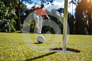 Golfer action to win after long putting golf ball on the green golf, lens flare on sun set evening time