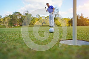 Golfer action to win after long putting golf ball on the green golf, lens flare on sun set evening time