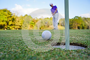 Golfer action to win after long putting golf ball on the green golf, lens flare on sun set evening time