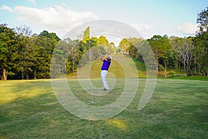 Golfer action to win after long putting golf ball on the green golf, lens flare on sun set evening time