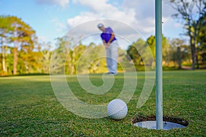 Golfer action to win after long putting golf ball on the green golf, lens flare on sun set evening time