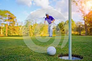 Golfer action to win after long putting golf ball on the green golf, lens flare on sun set evening time