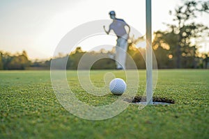 Golfer action to win after long putting golf ball on the green golf, lens flare on sun set evening time