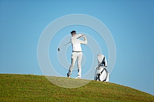 Golfer asia man approach on tee off for swing and hitting golf ball on slope green and looking fairway