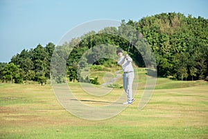 Golfer asian man use iron swing and hitting golf ball practice at golf driving range