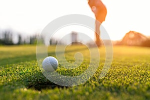 Golfer asian woman putting golf ball on the green golf on sun set evening time, select focus.