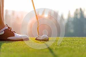 Golfer asian woman putting golf ball on the green golf on sun set evening time.