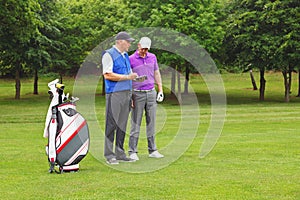 Golfer and caddy looking at a course guide