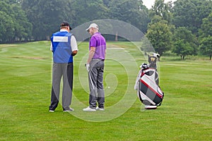 Golfer and caddy reading a course guide photo