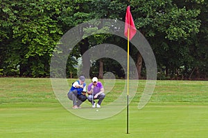 Golfer and caddy reading the line of putt