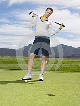 Golfer With Club Standing On Green