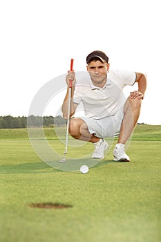 Golfer crouching and eyeing up putt