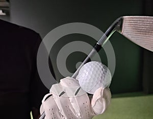 Golfer in golf gloves with iron club and equipment golf ball