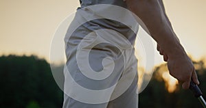 Golfer hand swinging club putter on sunset golf course. Man hitting ball outside