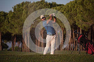 Golfer hitting a sand bunker shot on sunset