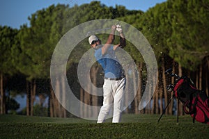 Golfer hitting a sand bunker shot on sunset