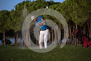 Golfer hitting a sand bunker shot on sunset