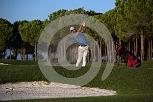 Golfer hitting a sand bunker shot on sunset