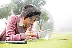 Golfer lying near golf ball