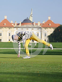 Golfer picking up the ball.