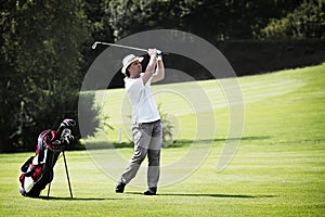 Golfer pitching at golf course.