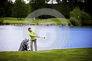 Golfer pitching at lake