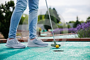 Golfer playing adventure or mini golf and trying putting ball into hole