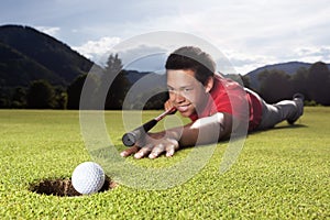 Golfer playing billiard on green.