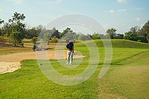 Golfer playing golf in the evening golf course, on sun set evening time. Man playing golf on a golf course in the sun