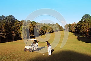 Golfer playing golf beside the golfcar in beautiful golf course in the evening golf course with sunshine
