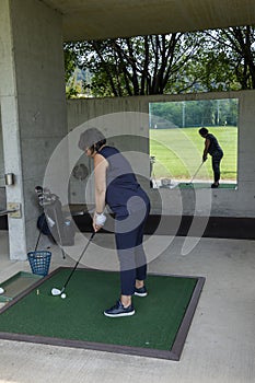 Golfer practice in driving range and a golf bag with golf clubs and mirror image