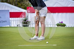 Golfer is pushing golf ball by golf club from tee boxes at golf course in competition game